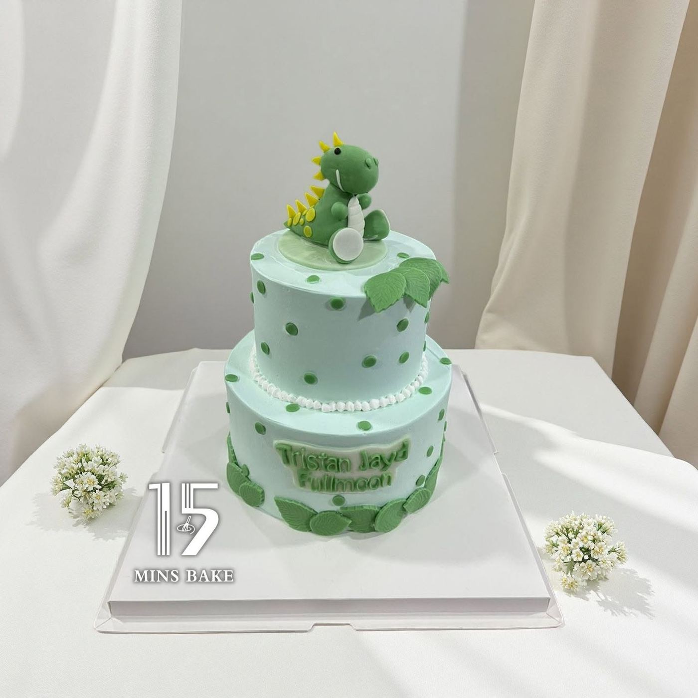 A two-tier custom cake with a fondant dinosaur topper for a full moon celebration